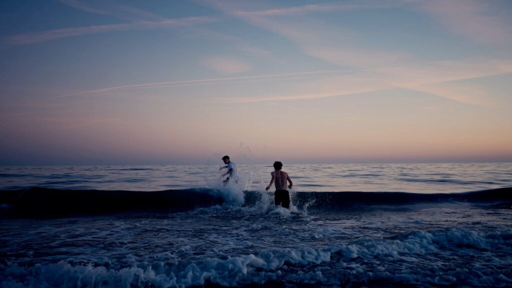 boys running into sea sunset